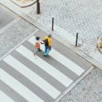 Pedestrians crossing at a busy city crosswalk with traffic nearby